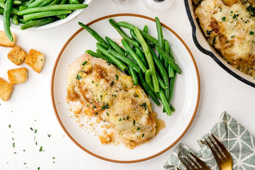 overhead of chicken breast covered with cheese and with green beans