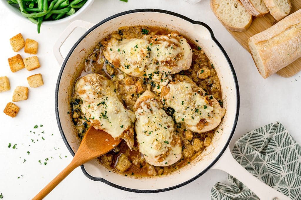 wooden spoon picking up chicken in a skillet