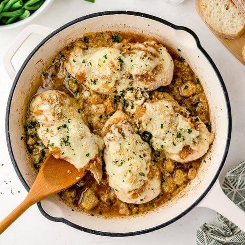 wooden spoon picking up chicken in a skillet