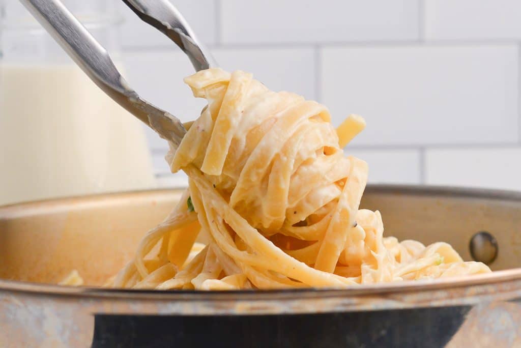 tongs twirling alfredo pasta