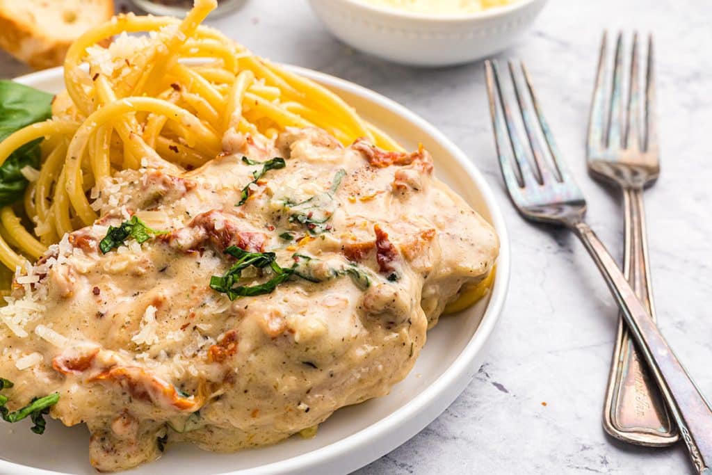 creamy tuscan chicken on a plate with pasta