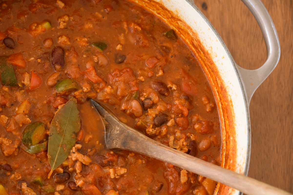 Full pot of Turkey Chili with Vegetables hot off the stove with serving spoon.