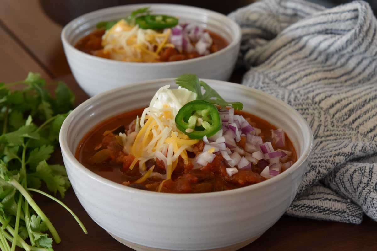 Two bowls of Turkey Chili with Vegetables and all the fixings. 