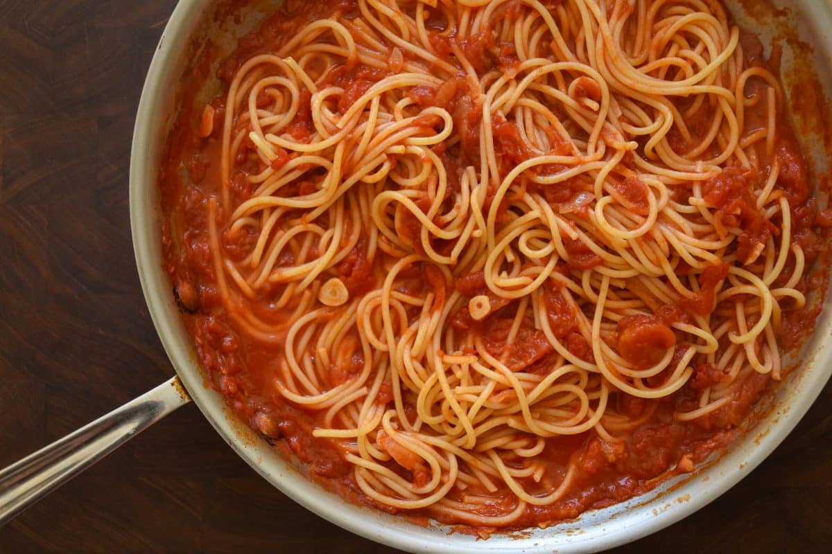 pan filled with spaghetti marinara on wooden cutting board