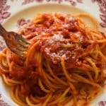 fork digging into spaghetti marinara on a plate